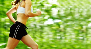 Beautiful young woman runner in a green forest.